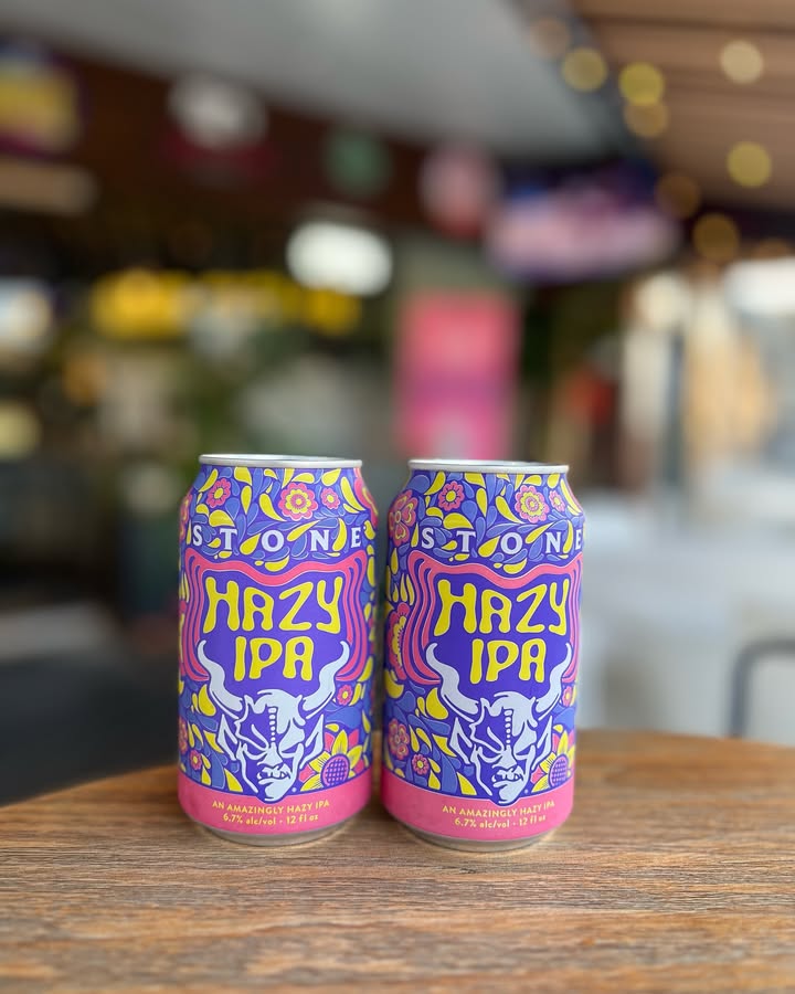 Two cans of Stone Hazy IPA on a wooden table